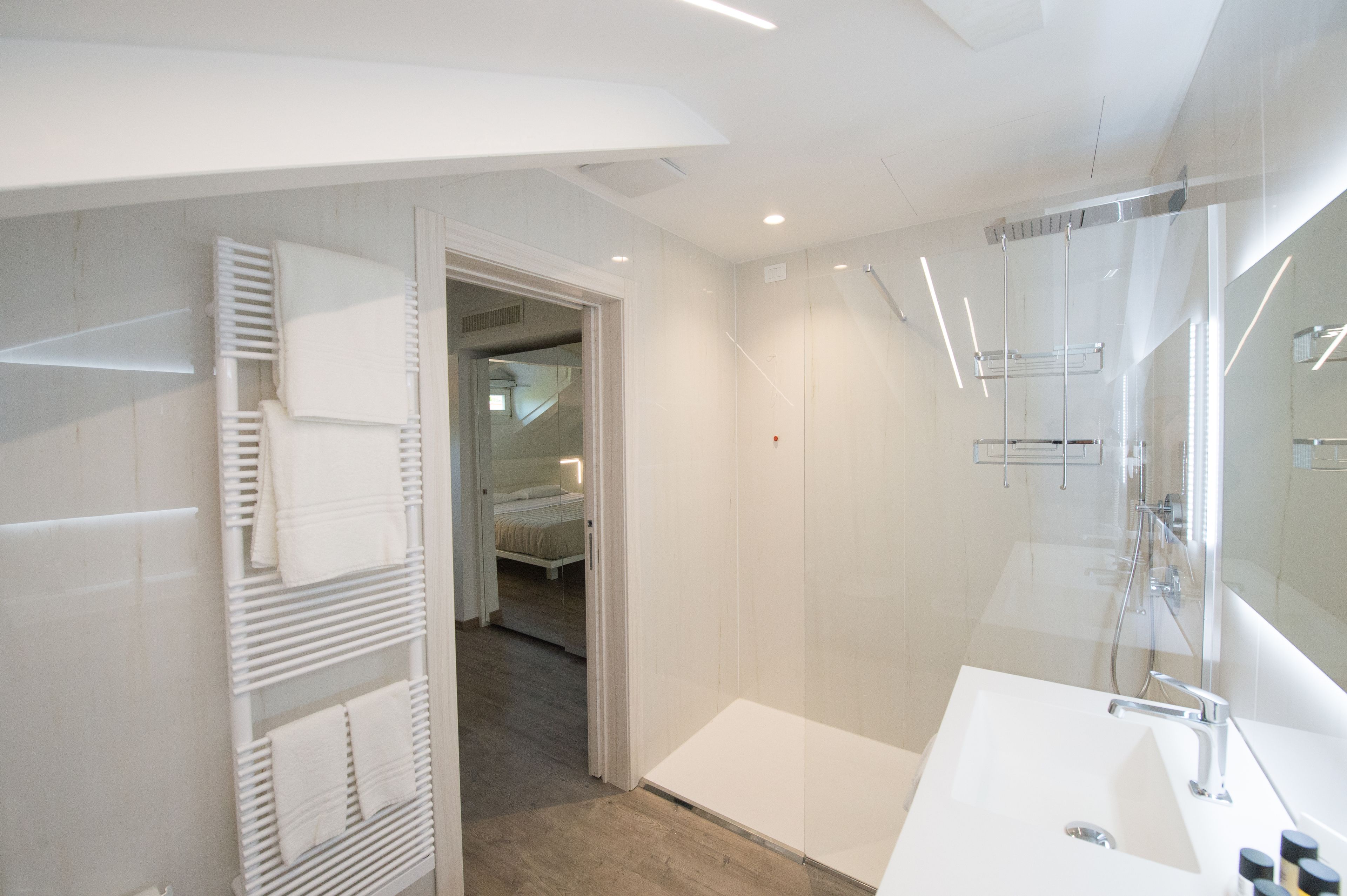 A modern bathroom with a large mirror, a white sink, and a towel rack.