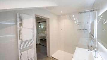 Een moderne badkamer met een grote spiegel, een witte wastafel en een handdoekrek.