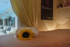 Una cama bien hecha con una toalla enrollada y un girasol.