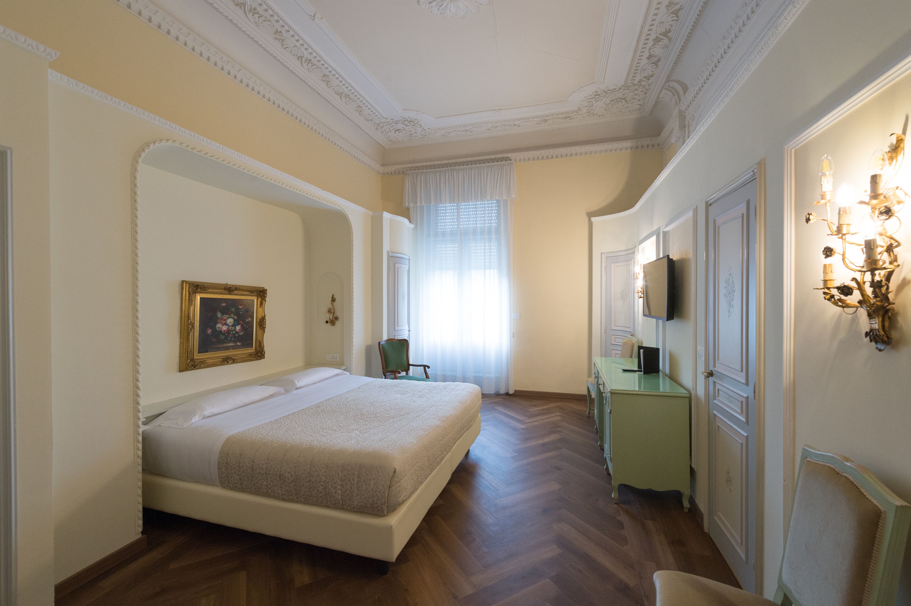 A bedroom with a bed, a chair, a dresser, and a television.