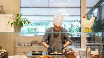 Un chef preparando comida en una cocina moderna con vistas al exterior, donde se aprecia vegetación.
