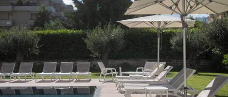 Un espace aménagé au bord de la piscine, avec des chaises longues et des parasols.