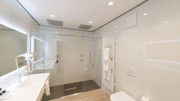 Un bagno moderno con cabina doccia in vetro, un lavandino bianco e un water.