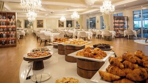 Un comedor espacioso con varias mesas, una gran variedad de pasteles y postres, y elegantes candelabros.