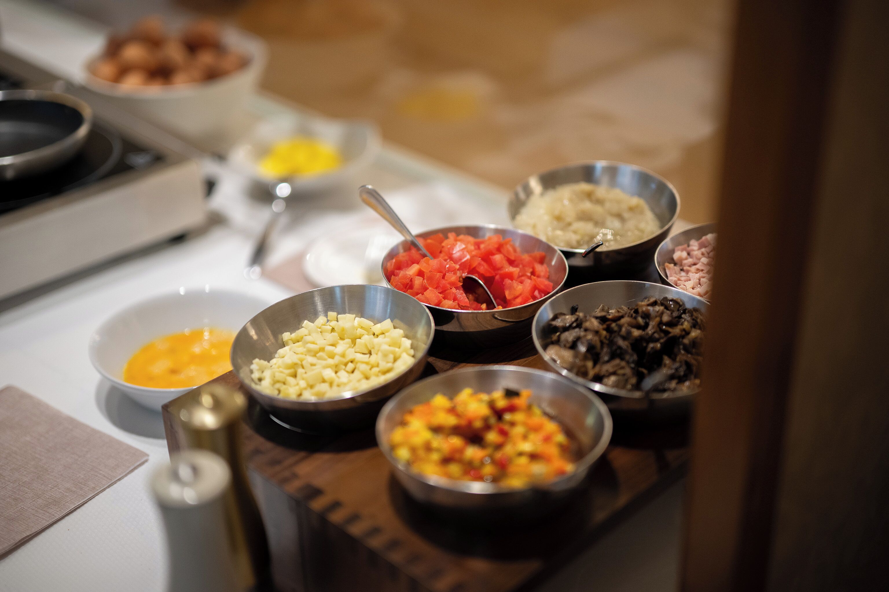 Diversi cibi in ciotole su un tavolo, tra cui pomodori a cubetti, formaggio e altri ingredienti.