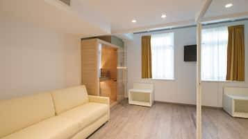 Una sala de estar moderna con un sofá, un mueble de madera empotrado, un radiador y un televisor montado en la pared.