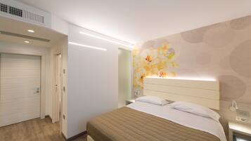 A hotel room with a bed, bedside table, and a wall-mounted light fixture.
