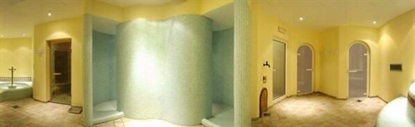A hotel room with a large, light-colored, cylindrical column, a small balcony, and a door leading to another room. - Grand Hotel Liberty (Riva del Garda)
