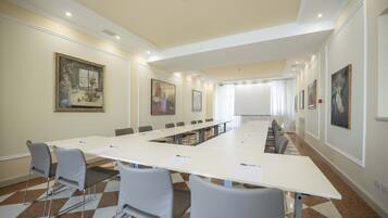 Un salón de conferencias con una mesa larga, sillas y obras de arte en las paredes.