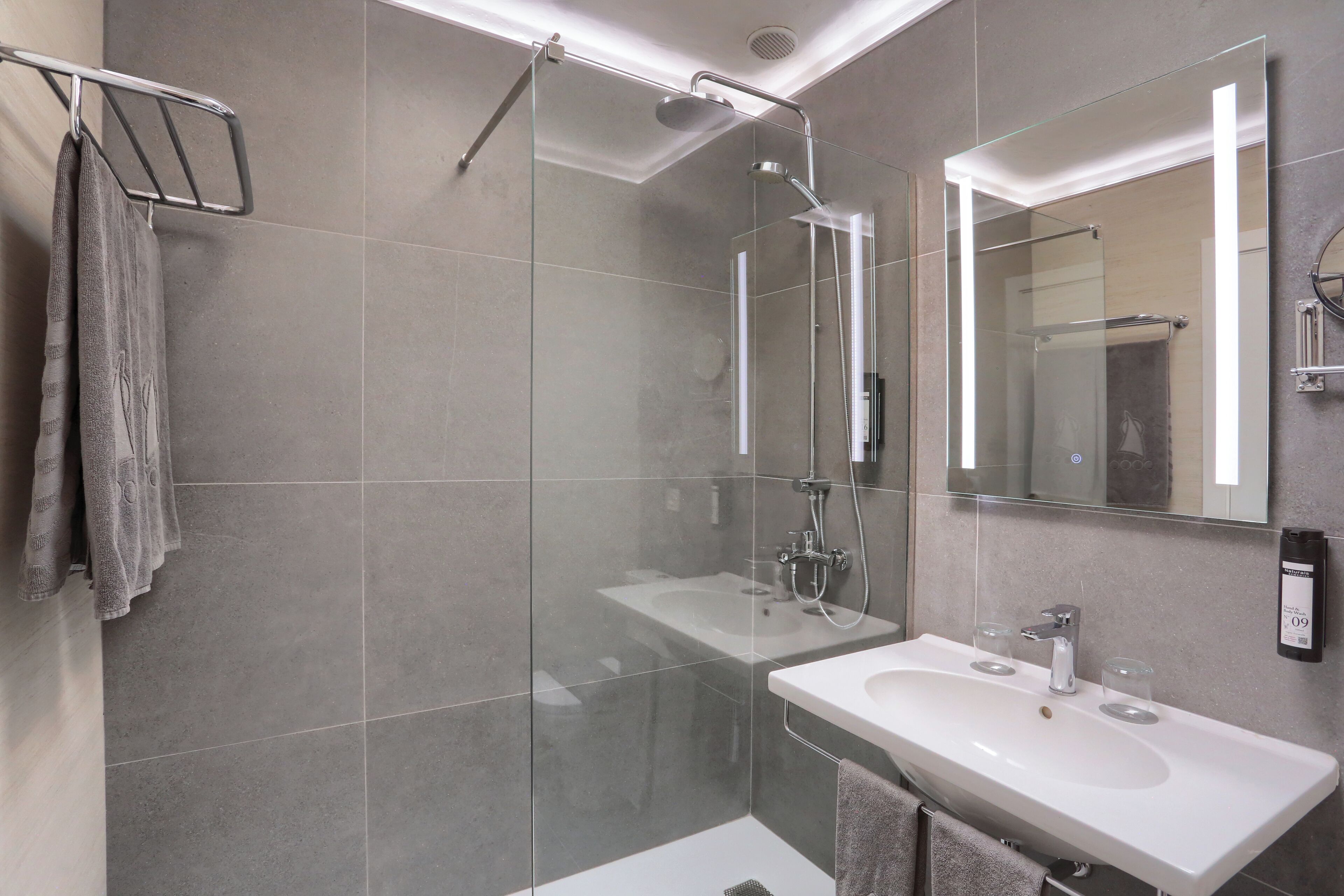 A modern bathroom with a glass-enclosed shower, a white sink, and a large mirror.