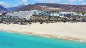 A coastal hotel with multiple white buildings, a sandy beach, and clear turquoise waters. - Apartamentos Garden & Sea Boutique Lodging by LIVVO (Pajara)