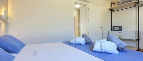 Ein Hotelzimmer mit Bett, Handtüchern, einer Klimaanlage, einem Nachttisch, einem Spiegel und einem am Wand montierten Fernseher.