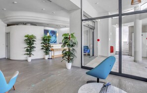A modern reception area with a curved desk, potted plants, and a large window. - Apartamentos Garden & Sea Boutique Lodging by LIVVO (Pajara)