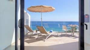 Ein Balkon mit Tisch, Stühlen und Sonnenschirm mit Blick auf das Meer.
