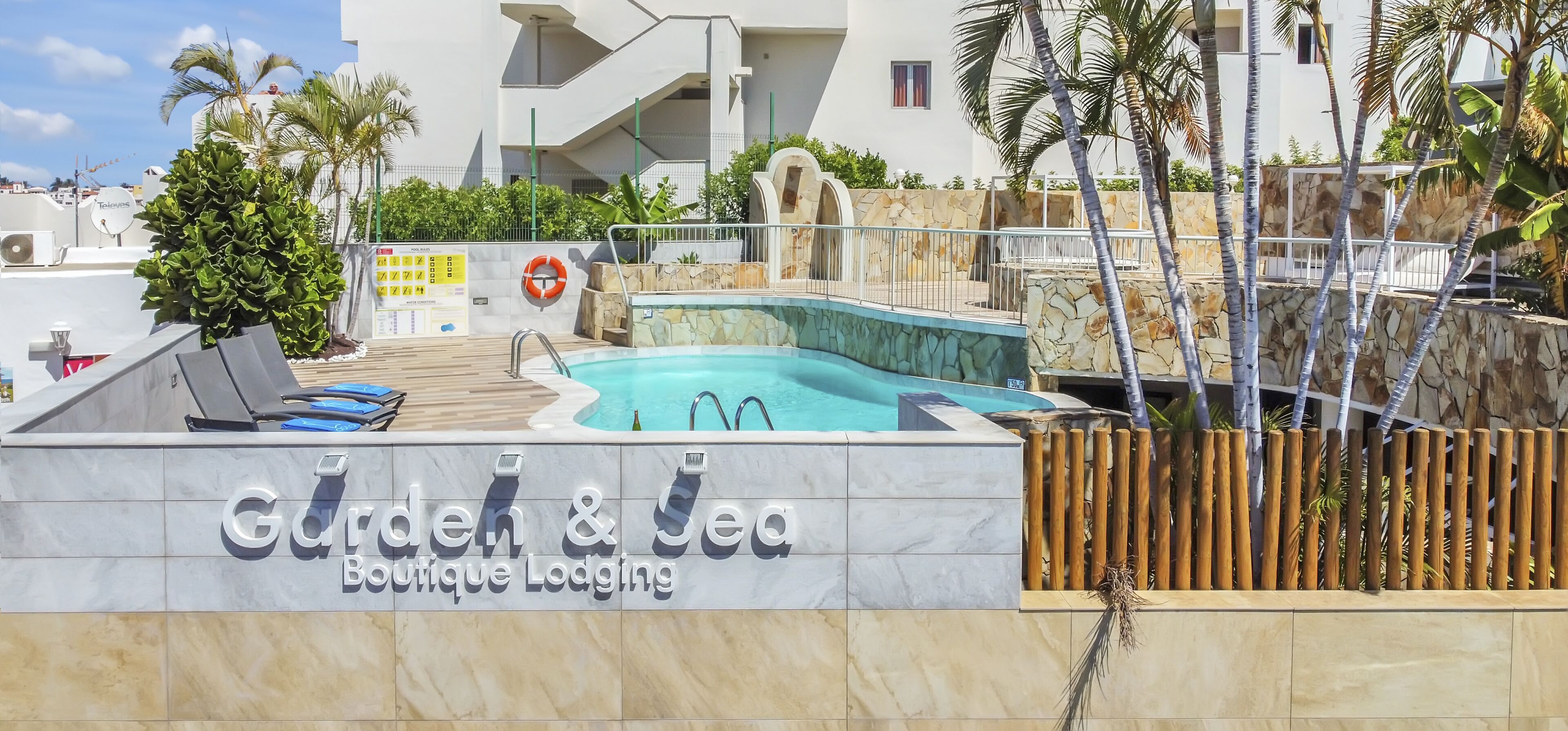 A pool area with a sign for 'Garden & Sea Boutique Lodging'.