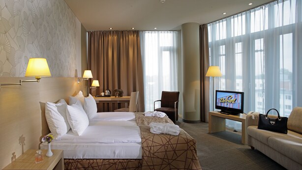 Une chambre d’hôtel avec deux lits, un bureau, une télévision et un canapé.