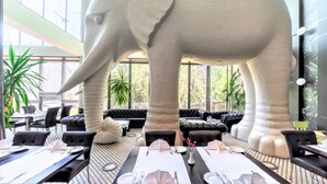 Un restaurant doté d’une grande sculpture d’éléphant, de sièges en cuir noir et d’un décor intérieur moderne.