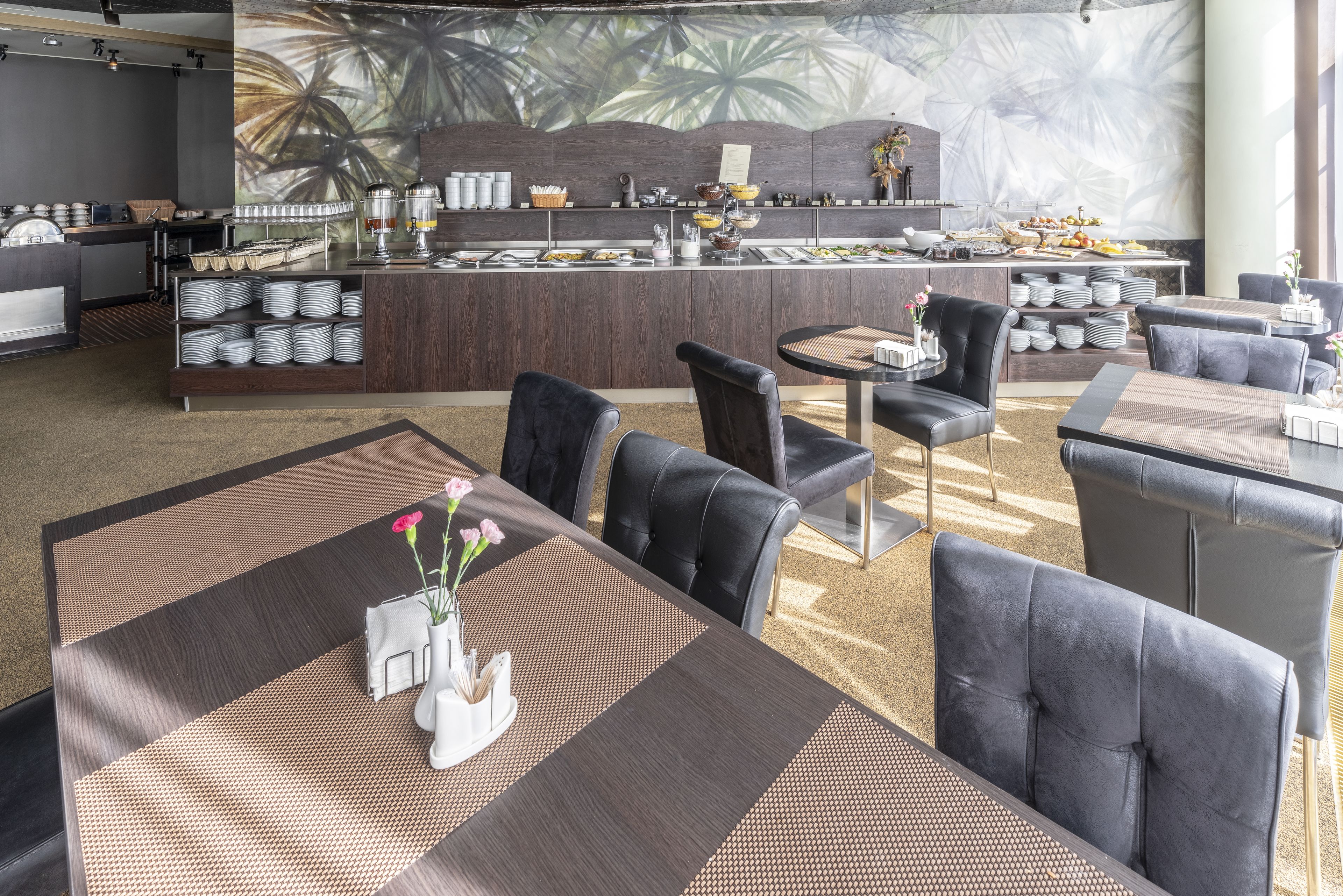 Eine moderne Hotelhalle mit einer zentralen Bar, Sitzgelegenheiten und einer großen Wanddekoration.