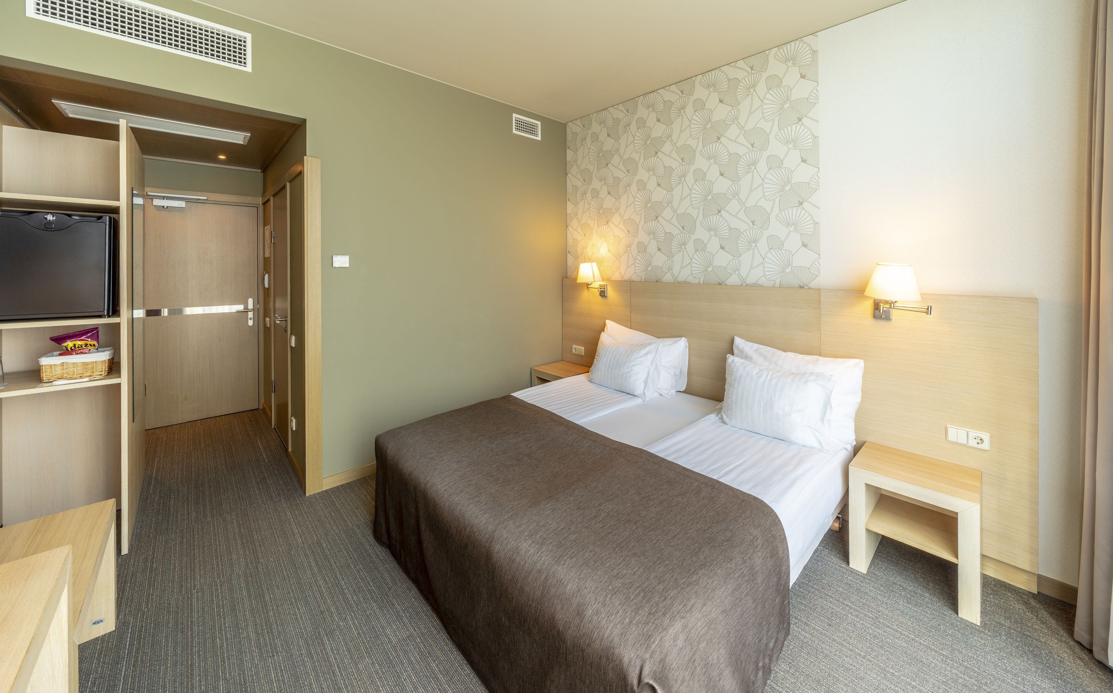 Ein Hotelzimmer mit Bett, Nachttischen, Fernseher und Kleiderschrank.