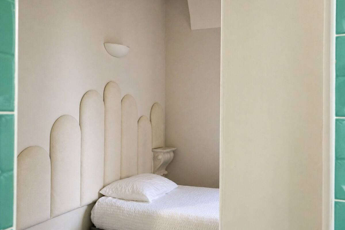 A bedroom with a bed, a nightstand, and a wall-mounted light fixture.