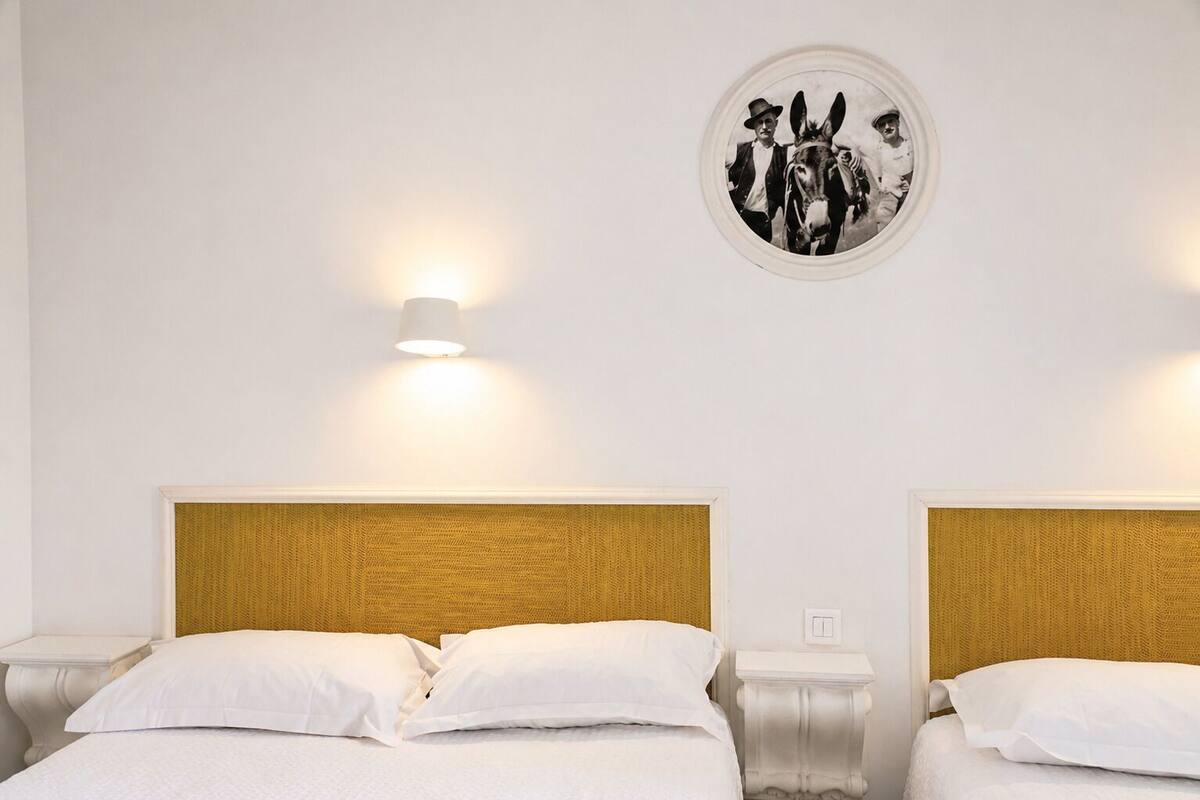 A hotel room with two beds, a round wall decoration, and a wall-mounted light fixture.