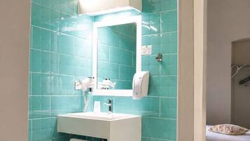 A bathroom with a white sink, a mirror, and a hand dryer.