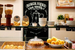 A breakfast buffet with labeled food items, including croissants, canister specialties, and fresh fruits. - Sud Hotel (Bastia)