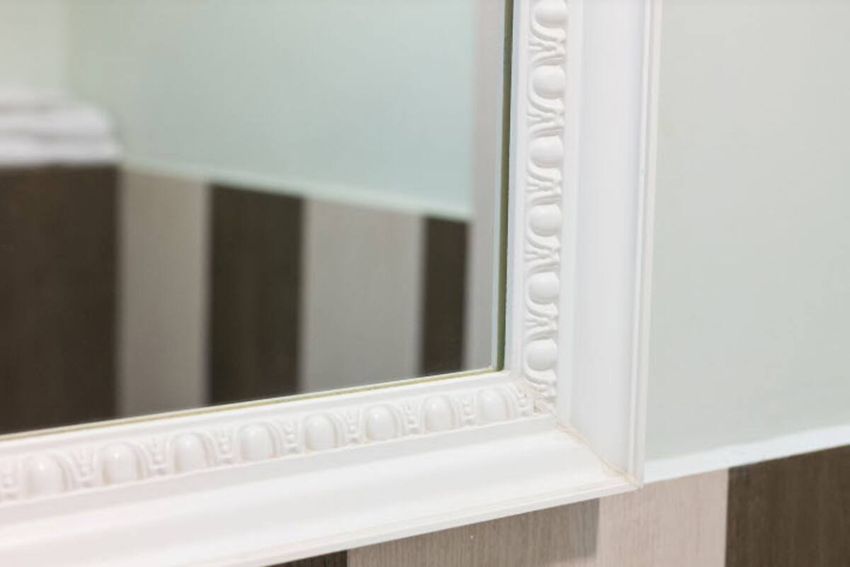 A bathroom mirror with a decorative frame.