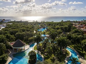 A resort with a large pool area, palm trees, and a view of the ocean. - Iberostar Waves Paraíso del Mar - All Inclusive (Playa del Carmen)