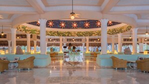 A spacious lobby with a central fountain, tropical murals, and seating areas.