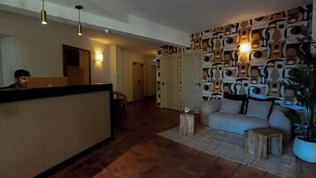 Un área de recepción con mostrador, sofá, planta en maceta y pared con diseño.