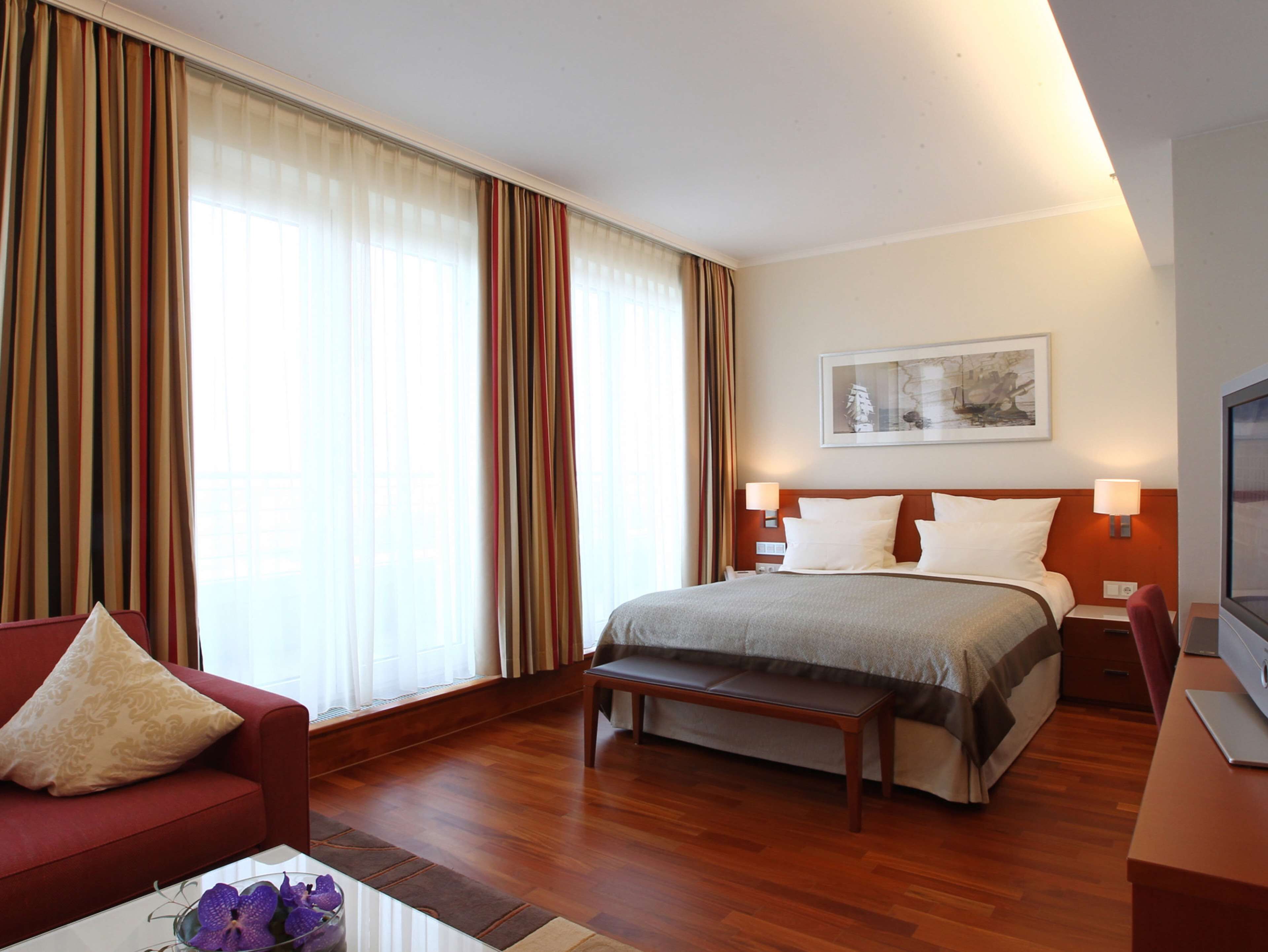 A hotel room with a bed, a desk, a chair, a bench, and a coffee table.
