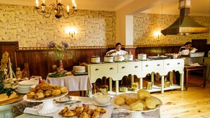 A buffet setup with various food items and a chef preparing food in the background.