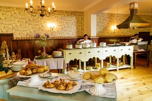 A buffet setup with various food items and a chef preparing food in the background. - Tsitsikamma Village Inn (Storms River)