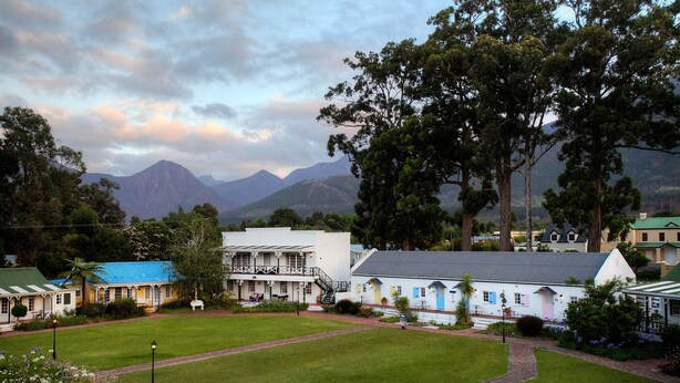 A hotel with a large lawn, multiple buildings, and mountains in the background.