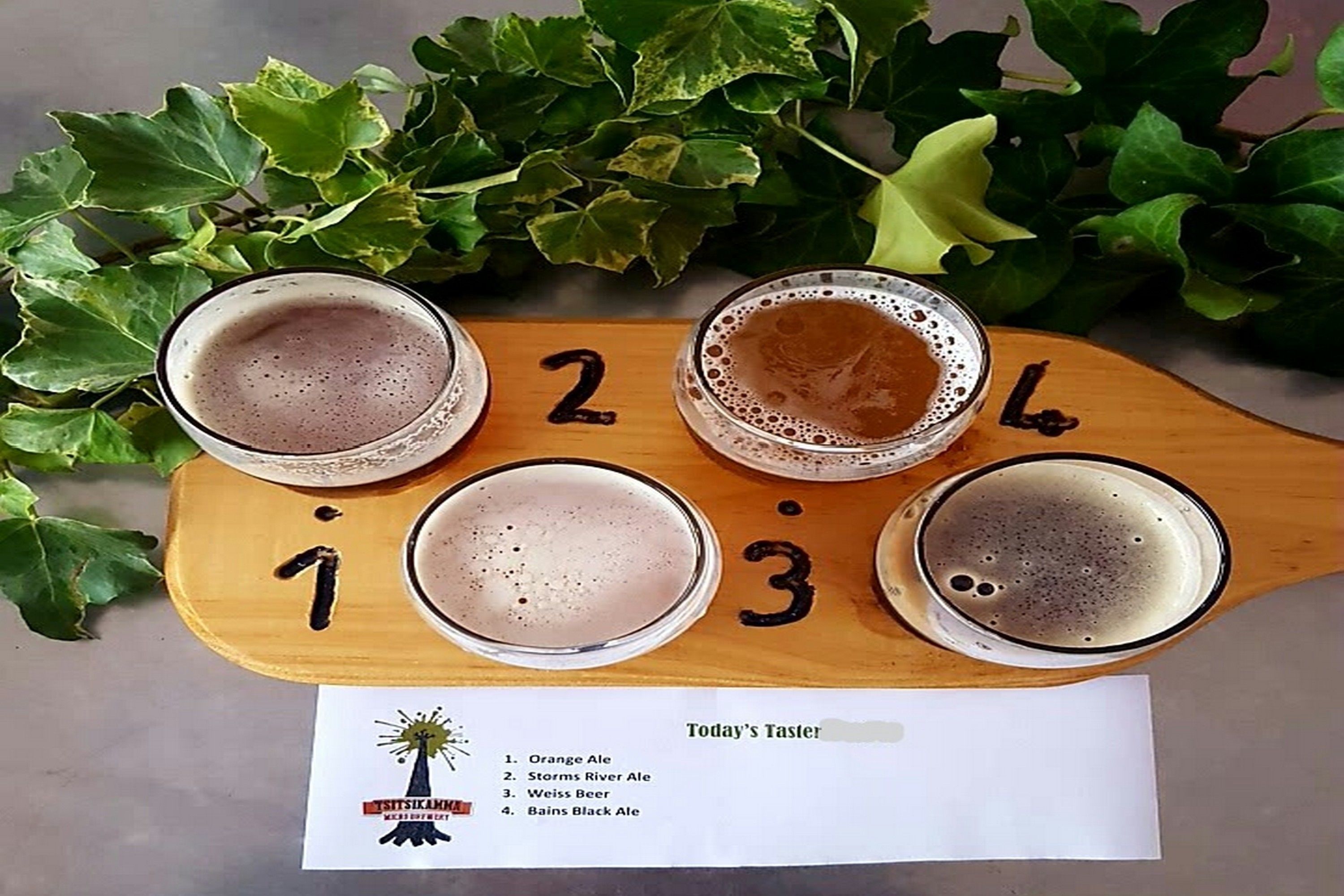 Quatre glaçons de cervesa sobre una taula de fusta amb els números de l'1 al 4, envoltats de fulles verdes.