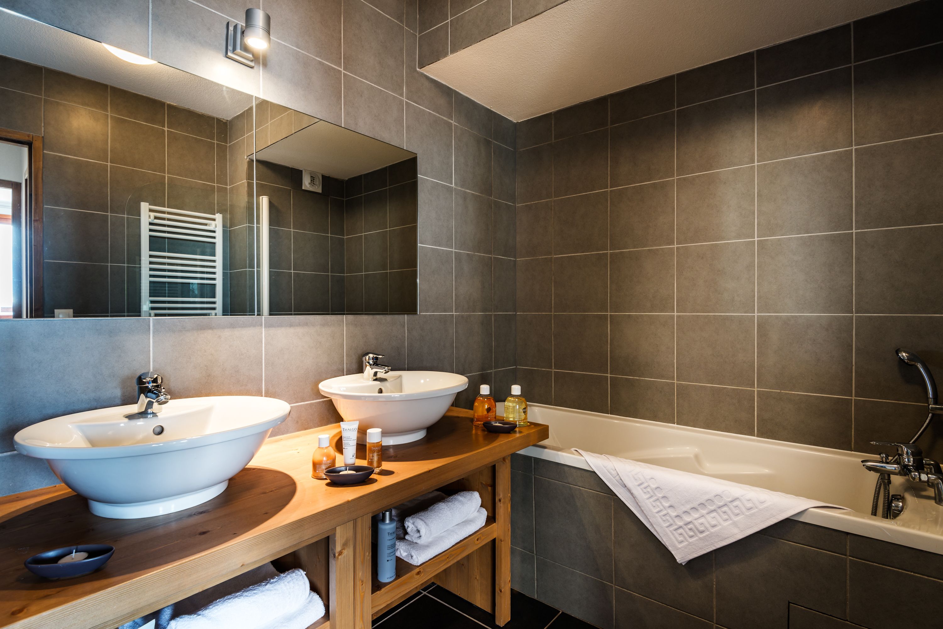 Un baño moderno con dos lavamanos, una bañera y un mueble de tocador de madera.