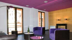 A modern living room with a purple sofa, a brown leather couch, and a round table with a candle. - Résidence Lagrange Vacances Le Pic de l'Ours (Font-Romeu-Odeillo-Via)