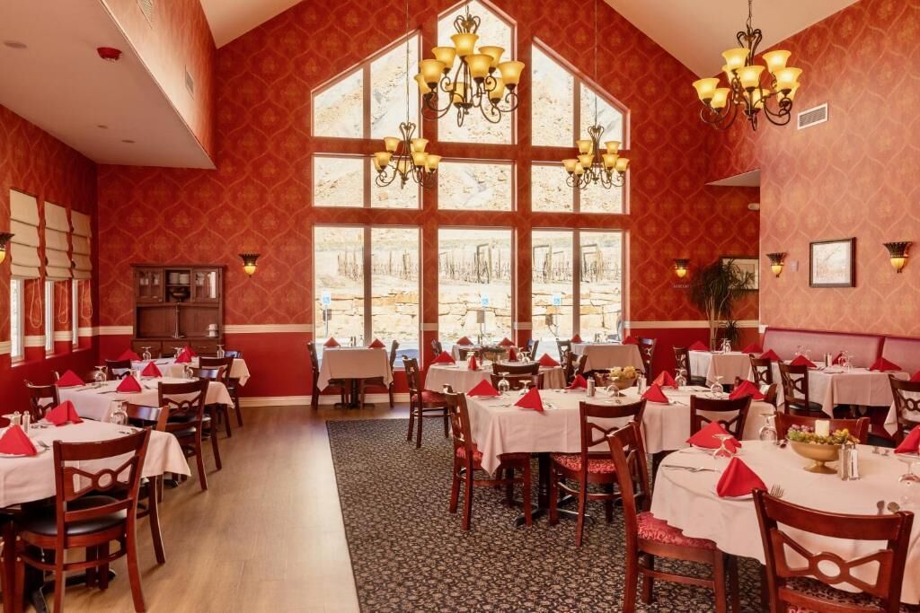 A dining area with multiple tables, red napkins, and chandeliers.