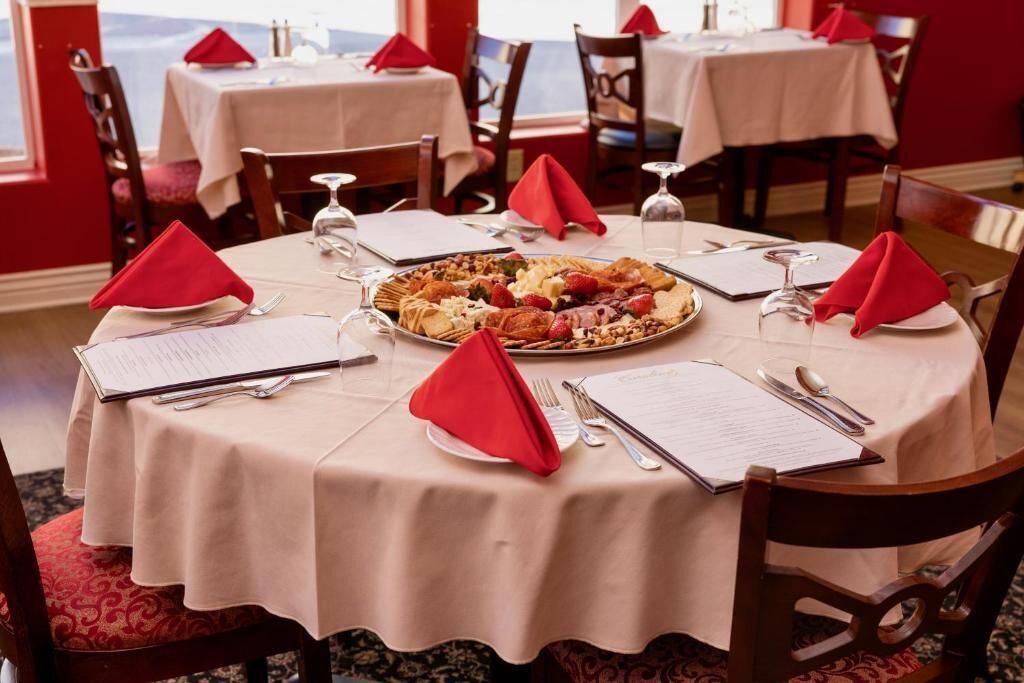 Een eettafel met een menukaart, een bord eten en rode servetten.