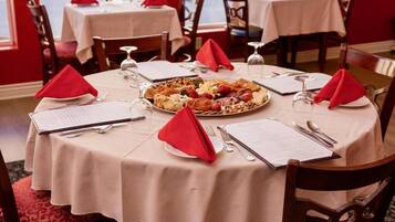 Una mesa de comedor con un menú, un plato de comida y servilletas rojas.