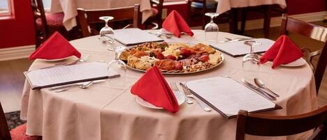 A dining table with a menu, a plate of food, and red napkins.