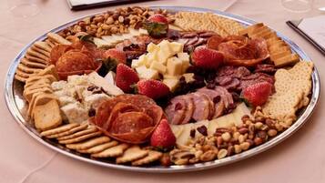 A platter with various cheeses, fruits, and nuts.