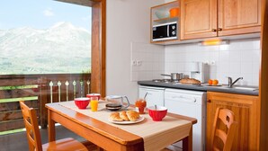 A kitchen with wooden cabinets, a stove, and a view of mountains. - Madame Vacances Résidence La Crête du Berger (Le Dévoluy)