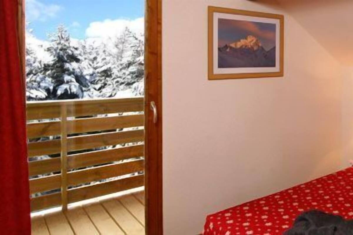 Une chambre à coucher avec une tête de lit en bois, deux lampes de chevet, une couvre-lit rouge et un tableau encadré au mur.