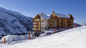 Ein mehrstöckiges Hotel mit einer Skipiste im Hintergrund.