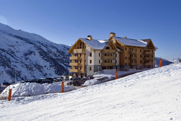 A multi-story hotel with a ski slope in the background.