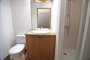 A bathroom with a wooden vanity, a toilet, and a shower.