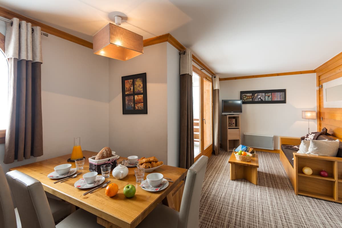 Une chambre d’hôtel avec un coin repas, un canapé et une télévision.