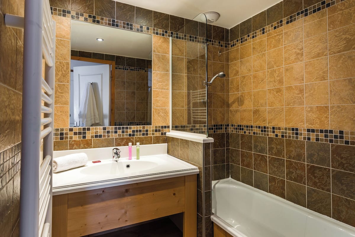 Une salle de bain avec un lavabo blanc, un miroir et une baignoire.
